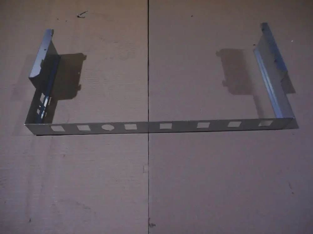 Metallische Halterung für Verrohrung, gefertigt von Remeha. Das Produkt hat eine flache, rechteckige Form mit seitlichen Erhöhungen und Ausschnitten auf der Oberfläche.